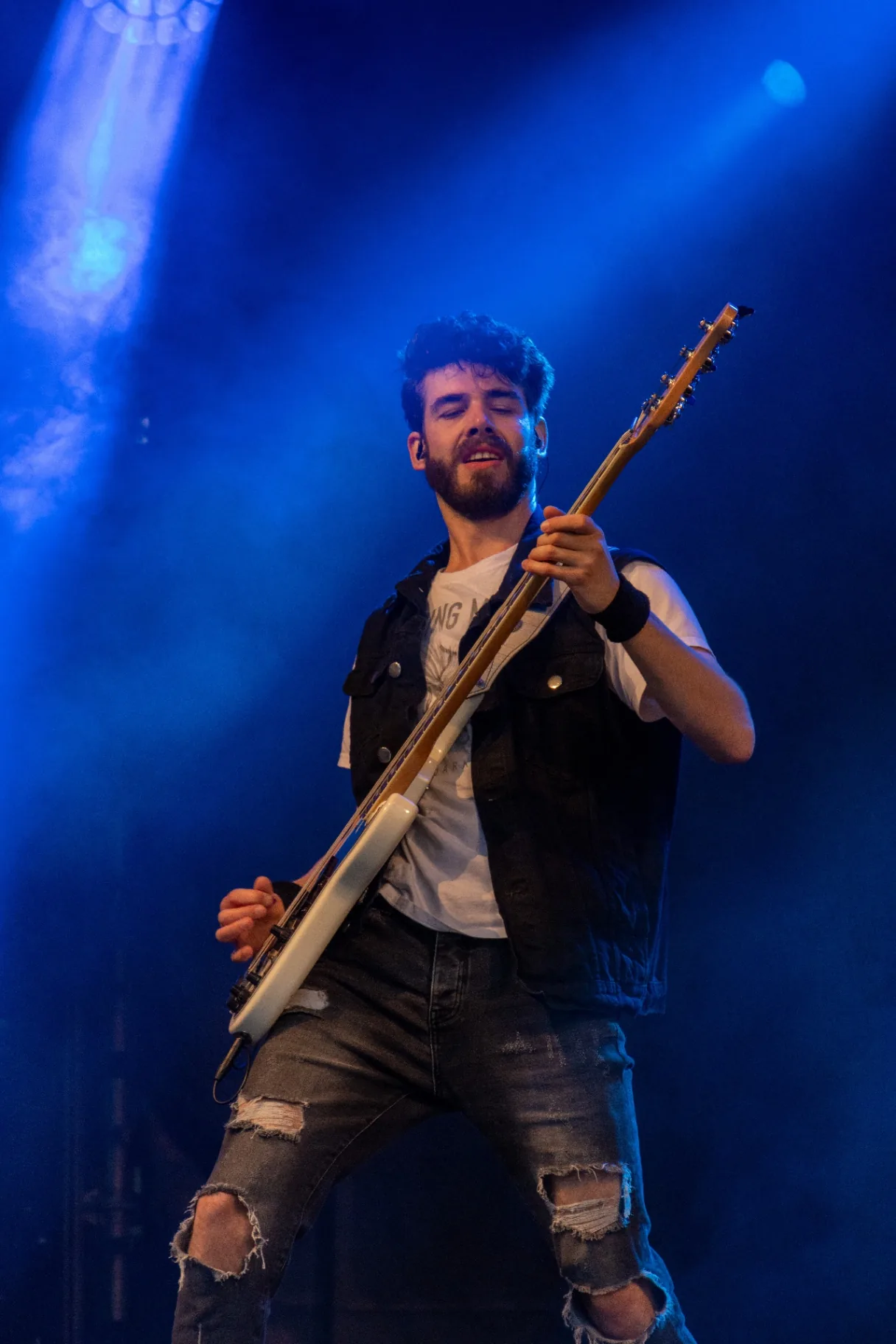 Bassist onder blauw podiumlicht met tegenlicht en rook