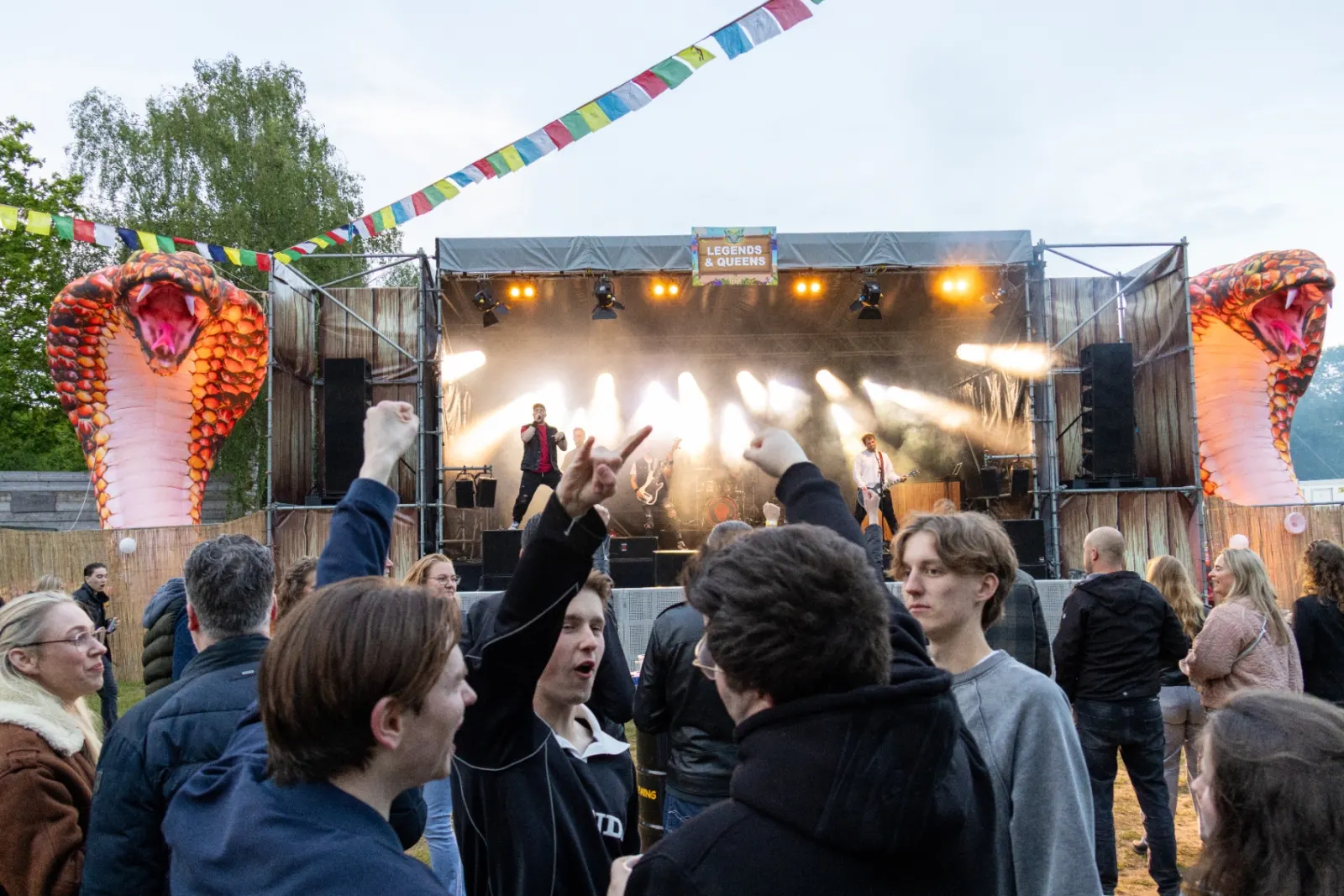 Band op festivalpodium met juichend publiek en grote slang-decors