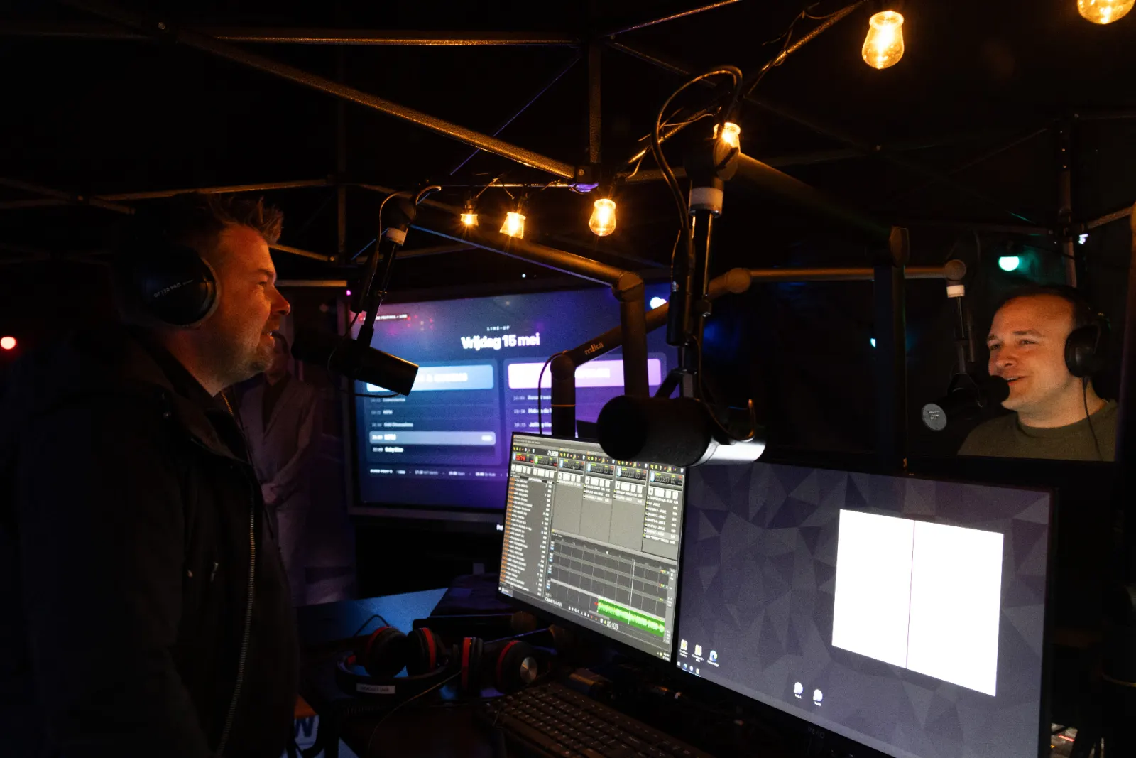 Twee presentatoren in een radiostudio met microfoons en koptelefoons