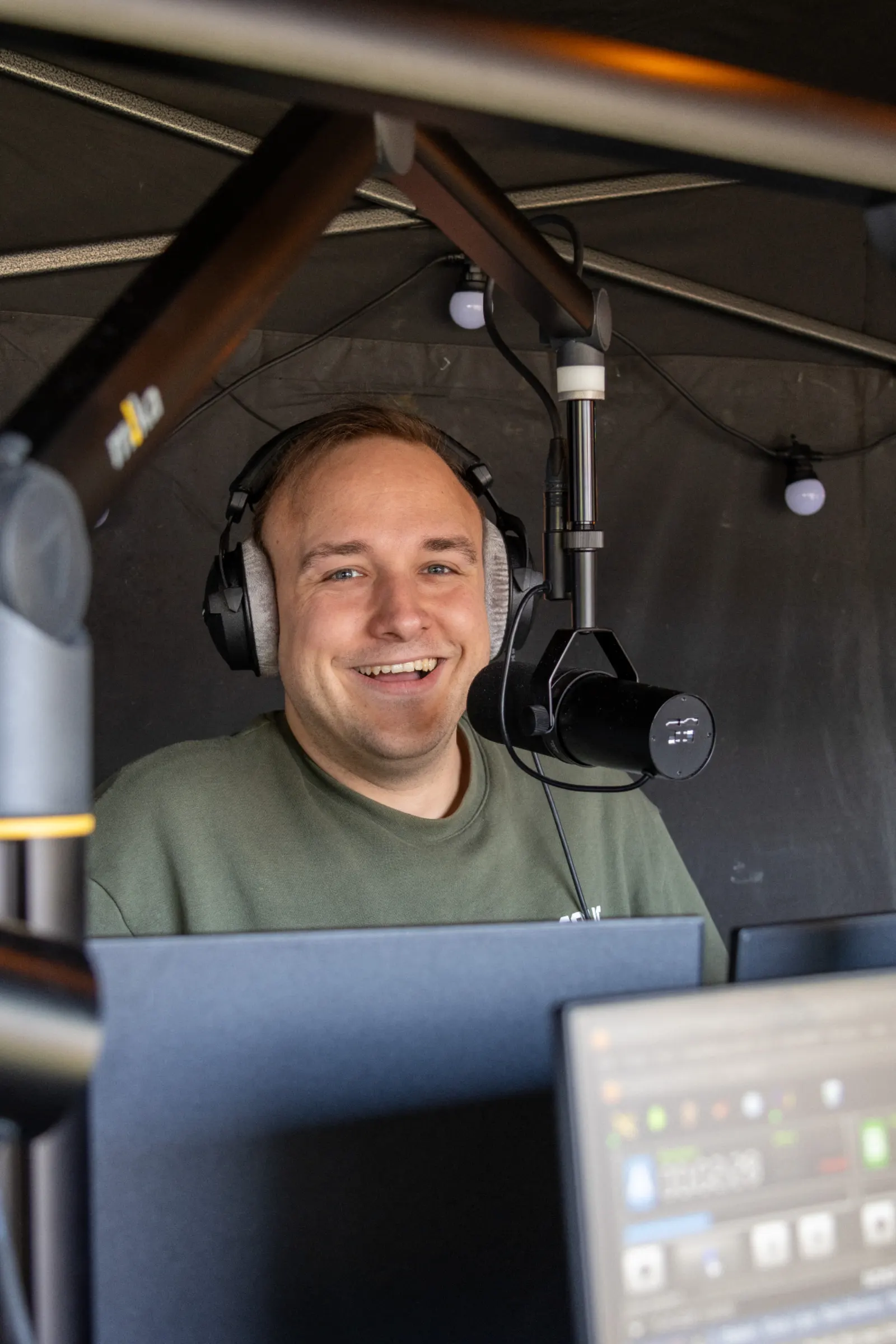Lachende radiopresentator met koptelefoon achter broadcast microfoon
