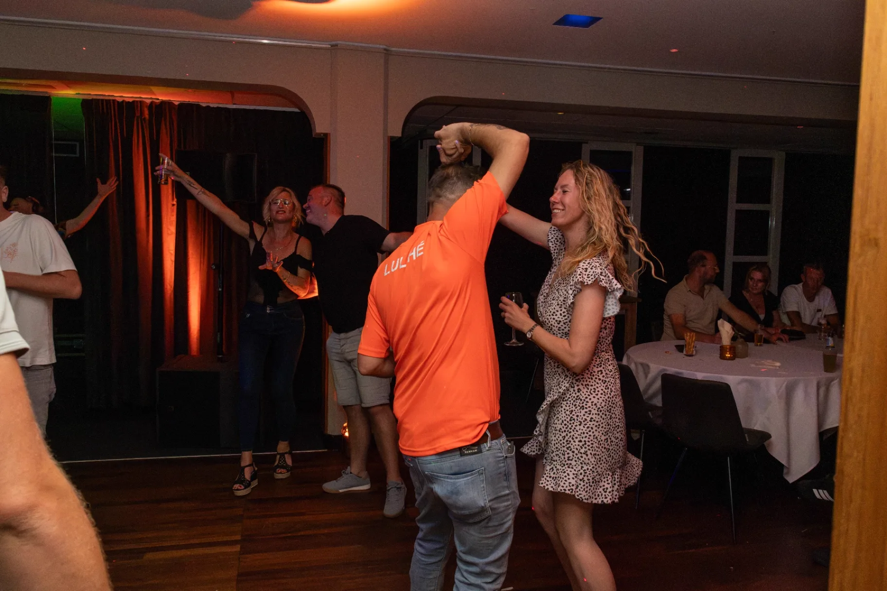 Lachend stel danst tijdens feest onder oranje sfeerverlichting