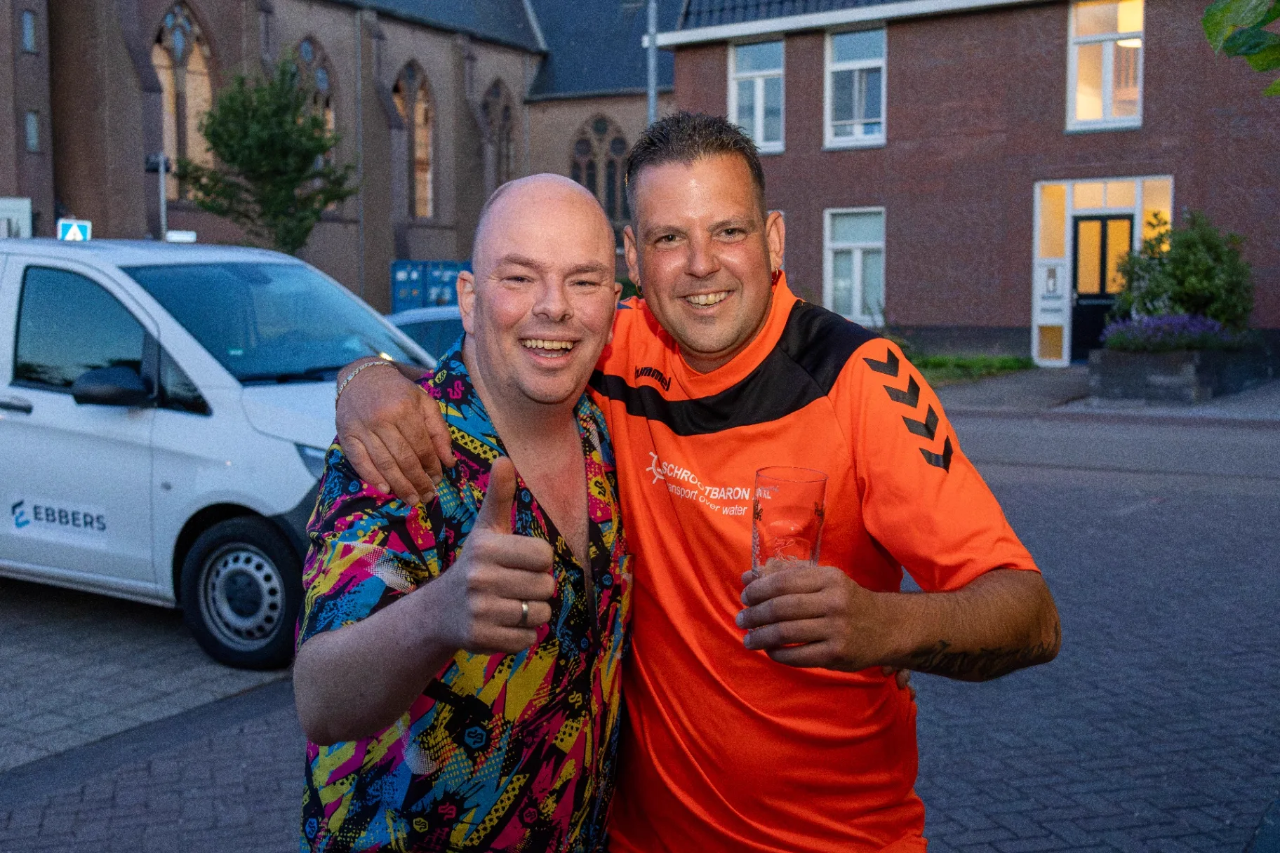 Twee lachende gasten met duim omhoog buiten op het feest bij zonsondergang