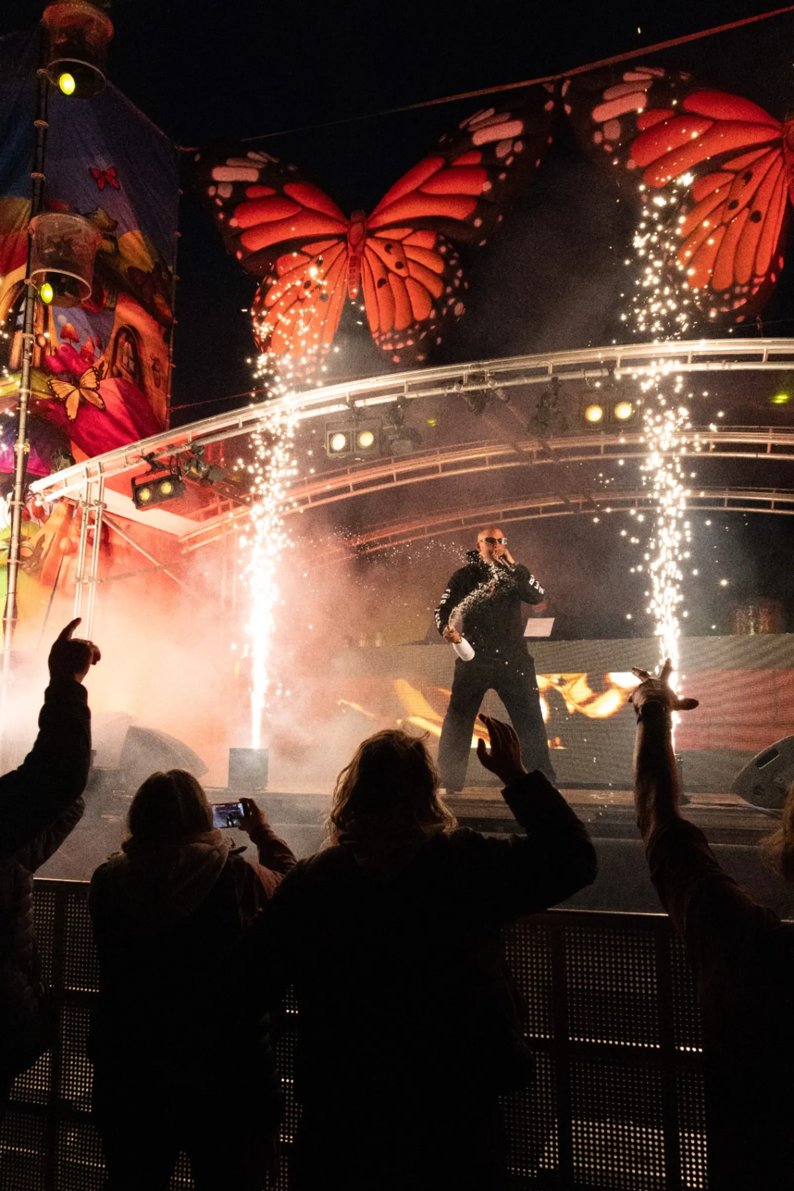 Artiest op festivalpodium met vuurwerk en grote vlinderdecors