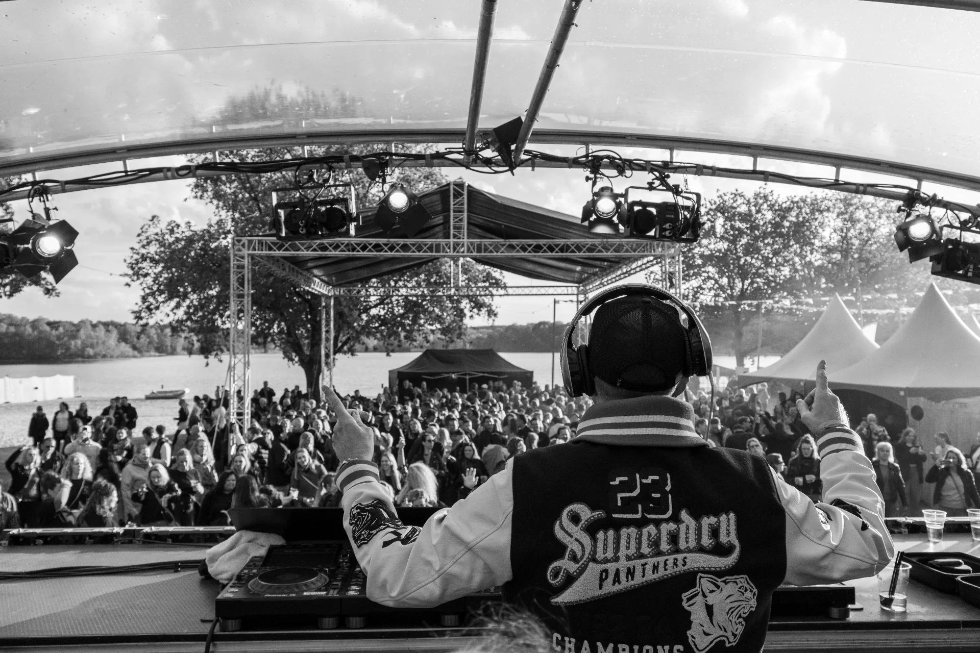Zwart-wit shot van DJ vanaf het podium met opgestoken handen in het publiek