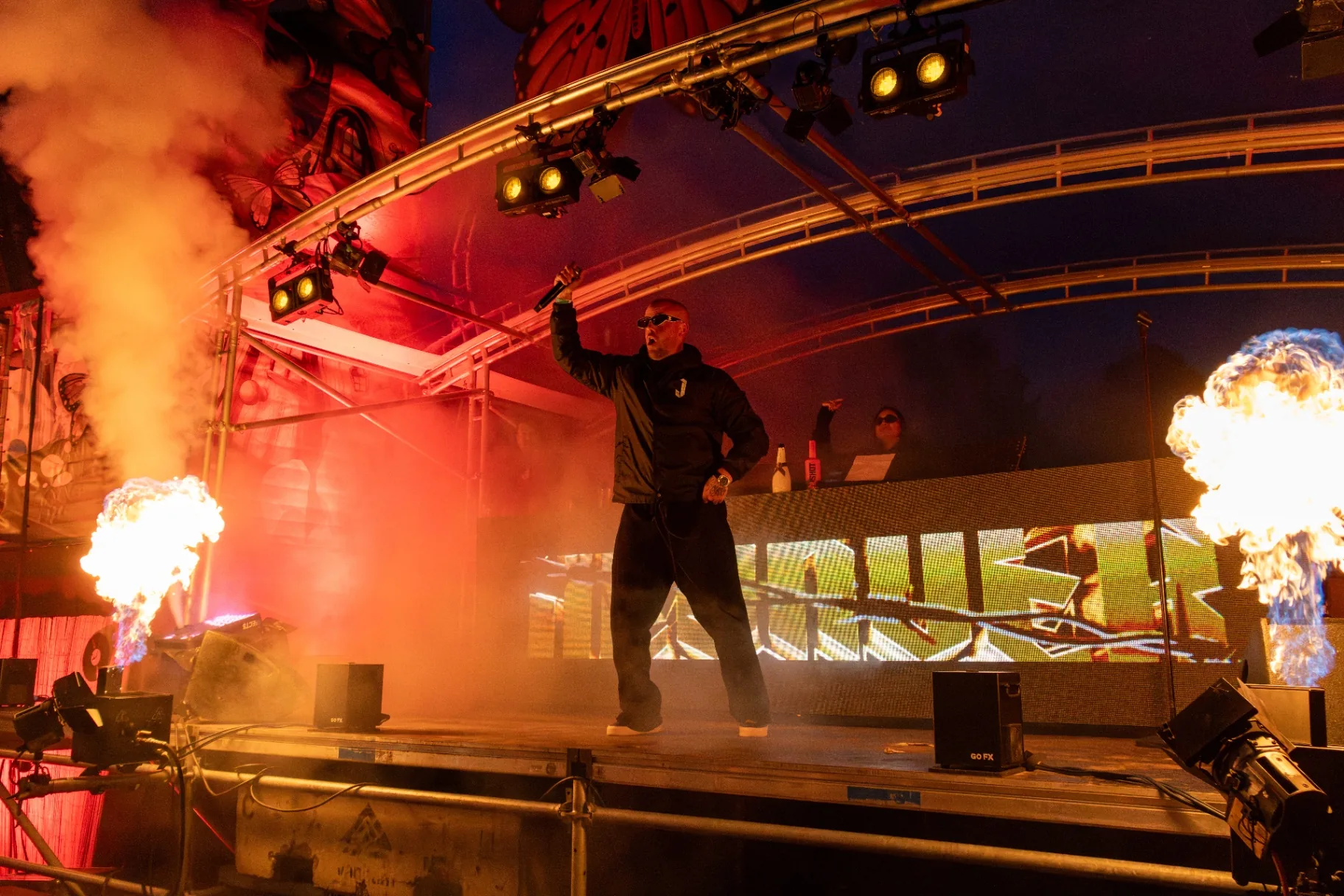 DJ met vuurkanonnen op podium met roze rook
