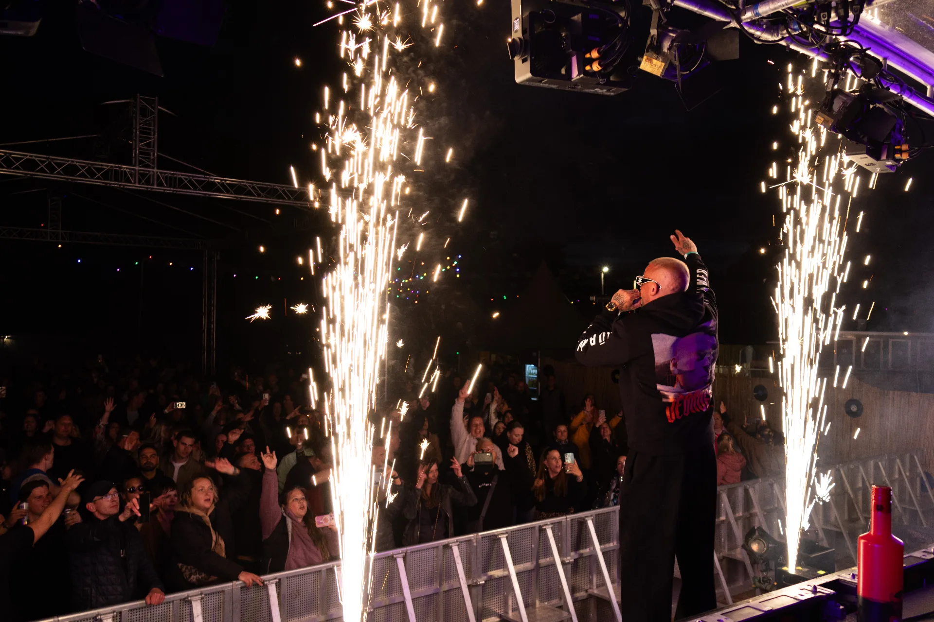 Festivalpodium met vuurkanonnen en vuurwerk fonteinen bij avondschemering