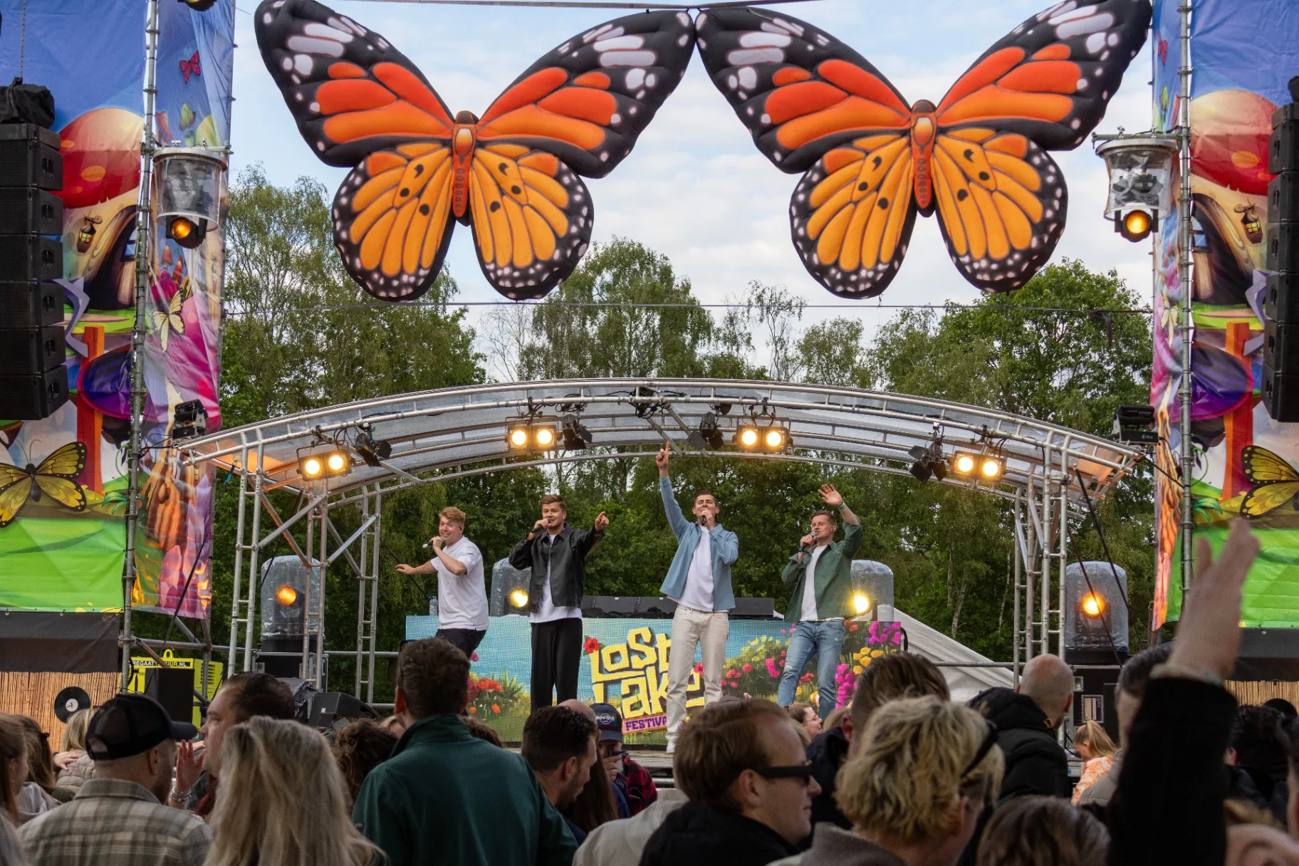 Festivalpodium met vlinderdecors en juichend publiek overdag