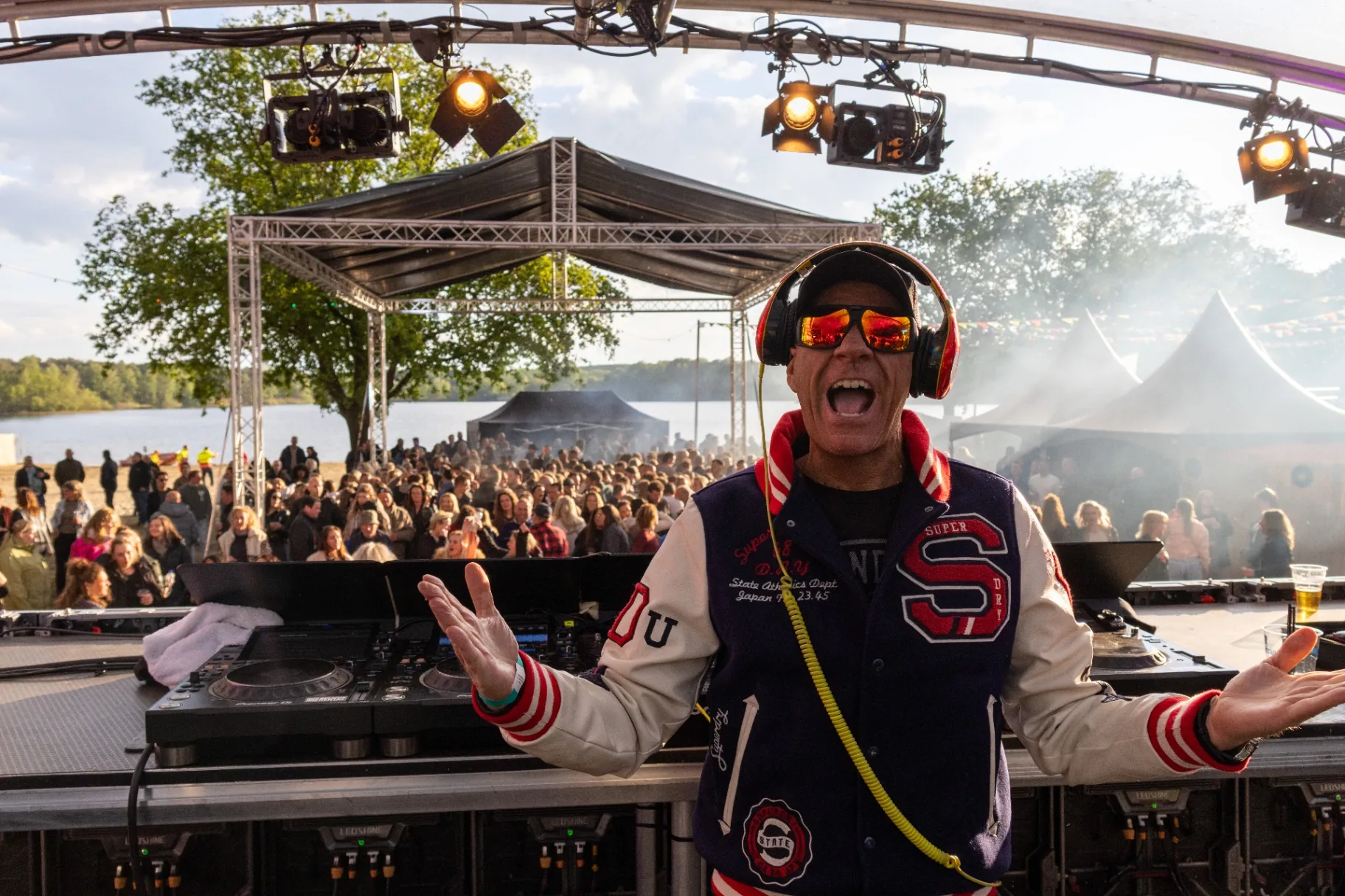 DJ in varsity jack met koptelefoon en juichend publiek