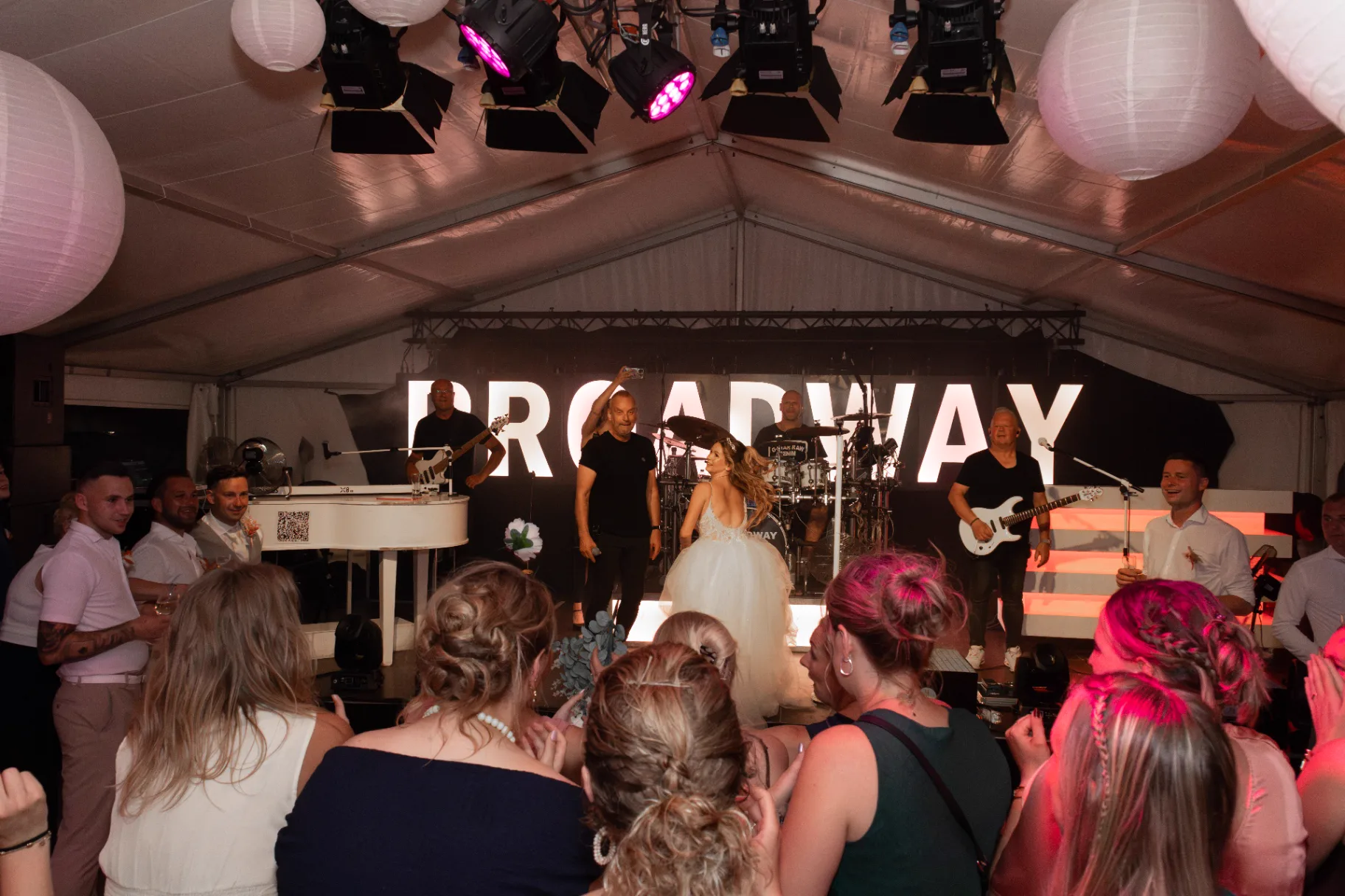 Bruid met liveband Broadway op podium tijdens bruiloftsfeest