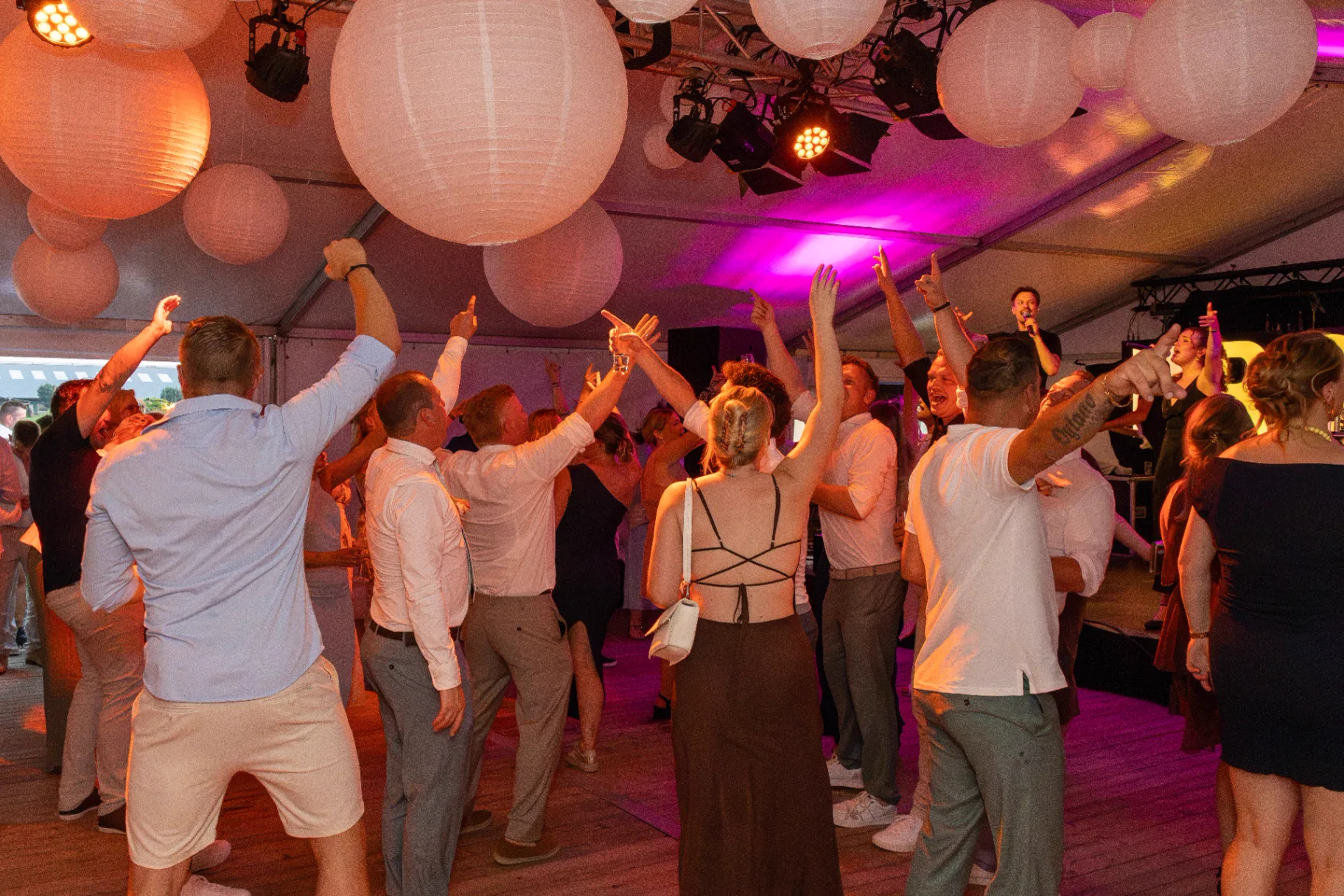 Juichende dansvloer met opgestoken armen tijdens bruiloftsfeest