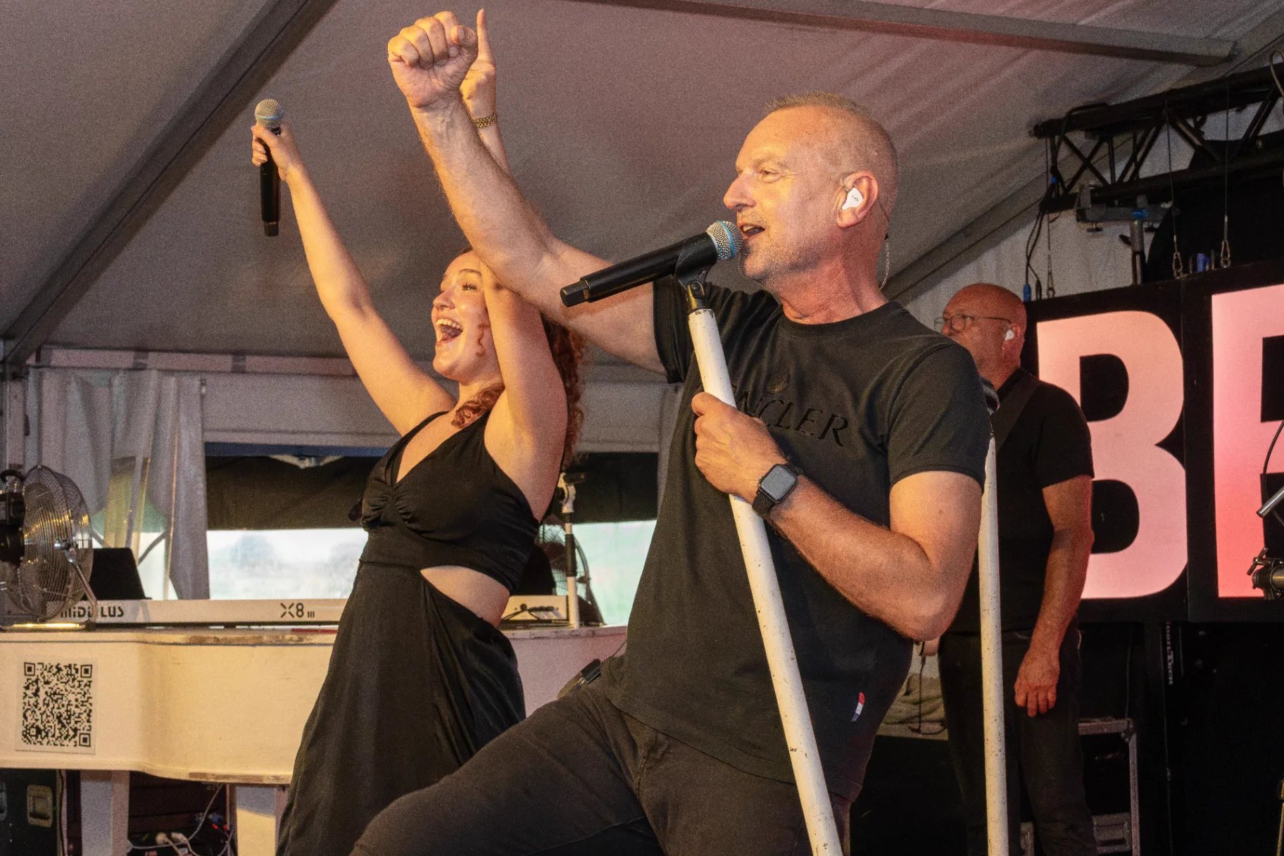 Zangers van liveband in actie met opgeheven armen op bruiloftspodium